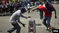 Demonstran di Port-au-Prince, Haiti, menari-nari di sekeliling peti mati palsu yang diberi lambang PBB dalam protes menentang PBB terkait merebaknya kolera di negara itu,