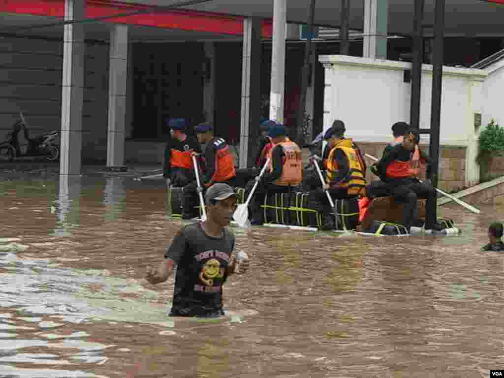 Warga di daerah Kampung Melayu-Tebet, Jakarta Selatan, mengungsi membawa barang-barangnya dengan menggunakan rakit buatan (13/1). (VOA/Ahadian Utama)