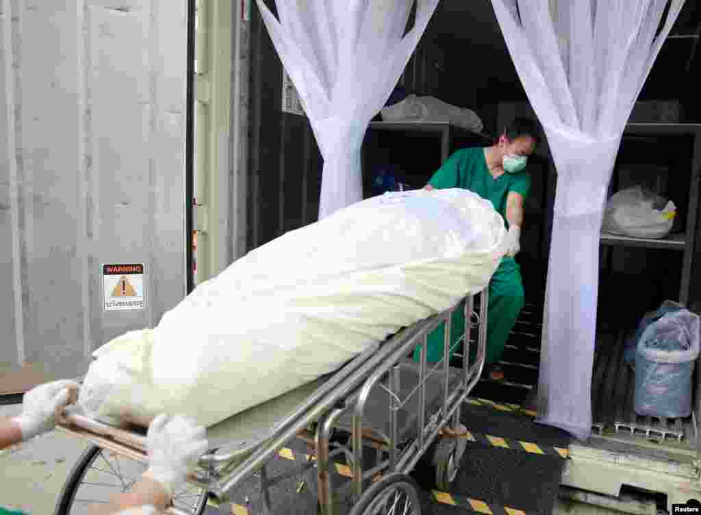 Health care workers move a dead body to a refrigerated container after a hospital morgue overwhelmed by COVID-19 deaths as the country struggles to deal with its biggest outbreak to date, in Pathum Thani, Thailand, July 31, 2021.