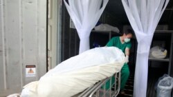 Health care workers move a dead body to a container after a hospital morgue overwhelmed by COVID-19 deaths begun to store bodies in refrigerated containers, as the country struggles to deal with its biggest outbreak to date, in Pathum Thani, Thailand July