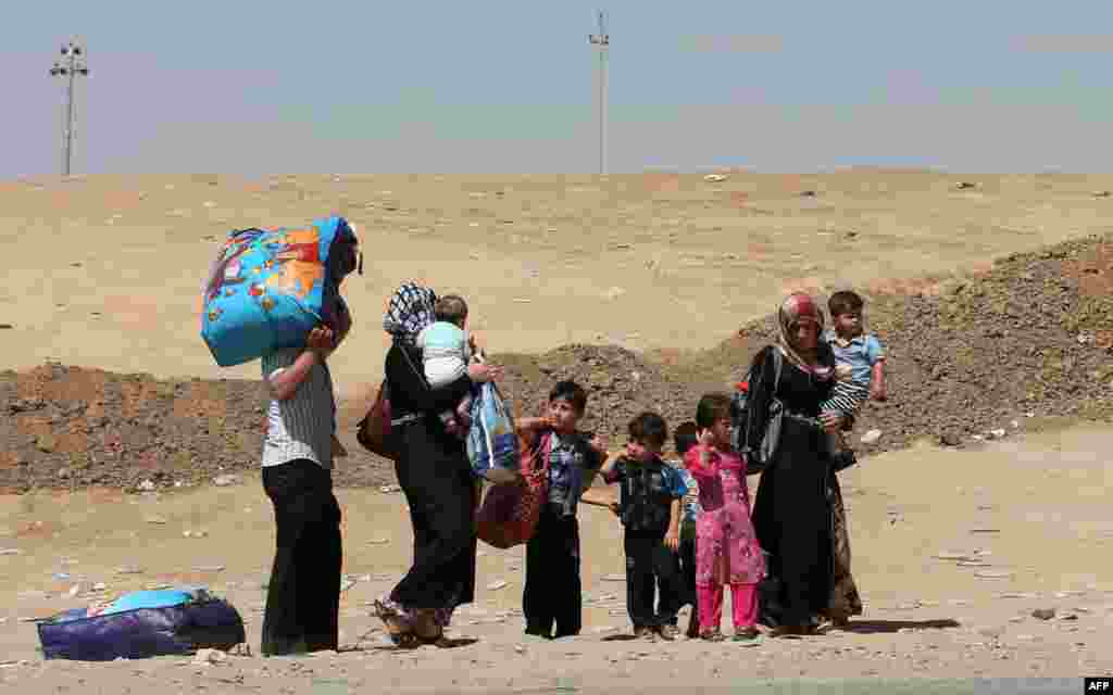Displaced people, who have fled violence in Iraq's northern Nineveh province, carry their belongings as they arrive in al-Hamdaniyah, 76 kms west of the Kurdish autonomous region's capital, Arbil.