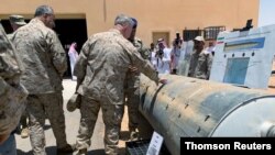 FILE - Saudi-led coalition officials show to U.S. Central Command chief General Kenneth McKenzie an exibit of weapons and missiles that is used by Houthi attacks against Saudi Arabia, in Riyadh.