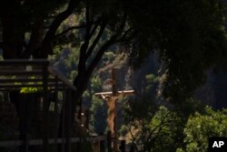 A cross with a statue of a crucified Jesus Christ hidden between the trees in the Saint Elisha Monastery, tucked into the scenic Kadisha Valley in Bcharre, Lebanon, on July 22, 2023.