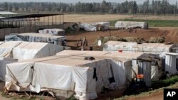 Syrian refugees walk outside their tents at a Syrian refugee camp in the eastern Lebanese town of Majdal Anjar, Lebanon, June 19, 2014.