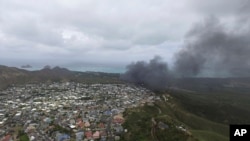 En esta foto tomada por un drone, se ve el humo elevándose de la aeronave Osprey de la Infantería de Marina de EE.UU. que realizó un aterrizaje de emergencia en Hawaii, el domingo, 17 de mayo, de 2015.