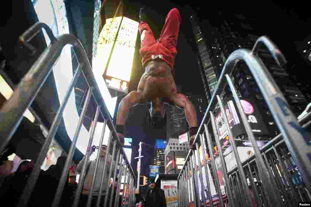 A man, who gave his name as Wildcat, works out on NYPD crowd control barricades in the rain in Times Square in New York, Dec. 1, 2014. Wildcat says he works out in public places to encourage others to get healthy without the need for fancy equipment.