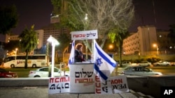 FILE - An Israeli peace activist hands out signs prior to a protest in Tel Aviv, Israel, Jan. 15, 2011. A newly-proposed Israeli law would require nonprofit groups to disclose foreign sources of funding.