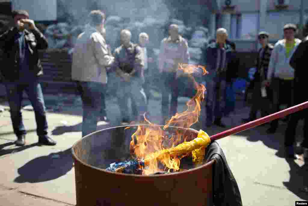 A Ukrainian flag burns outside the city hall in Mariupol, May 7, 2014.