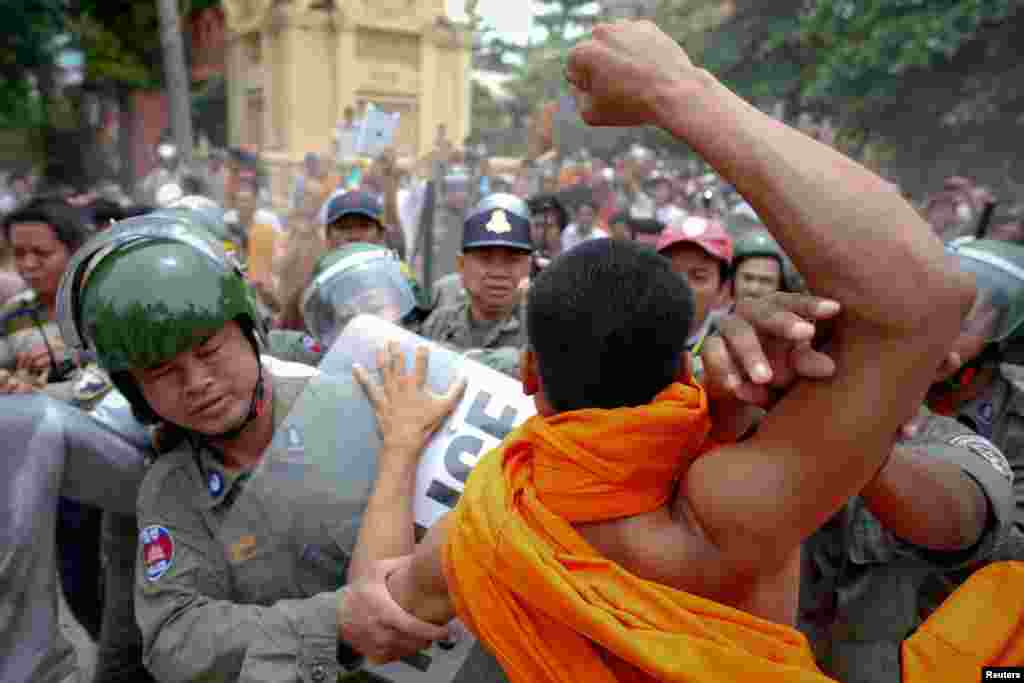 Riot policemen protect a man accused of trying to hit a Buddhist monk, during protests against alleged election irregularities in Phnom Penh July 28, 2013. 