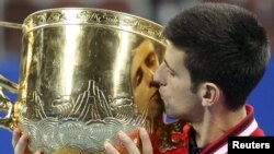 Novak Djokovic dari Serbia mencium pialanya setelah memenangkan final tunggal putra China Terbuka melawan Rafael Nadal dari Spanyol di Beijing (11/10). 