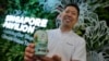 Nick Chow, part of the COP29 Singapore Pavilion team, poses for a photo with NEWBrew, beer made with treated wastewater, during the COP29 UN Climate Summit, Nov. 15, 2024, in Baku, Azerbaijan.