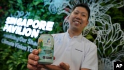 Nick Chow, part of the COP29 Singapore Pavilion team, poses for a photo with NEWBrew, beer made with treated wastewater, during the COP29 UN Climate Summit, Nov. 15, 2024, in Baku, Azerbaijan.