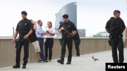 Armed Catalan Mossos d'Esquadra officers patrol along La Barceloneta beach in Barcelona, Spain, Aug. 19, 2017