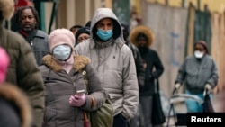 People wearing protective masks wait in line for free masks and pre-packaged meals during the outbreak of the coronavirus disease (COVID-19) in New York City, U.S., April 18, 2020. REUTERS/Jeenah Moon