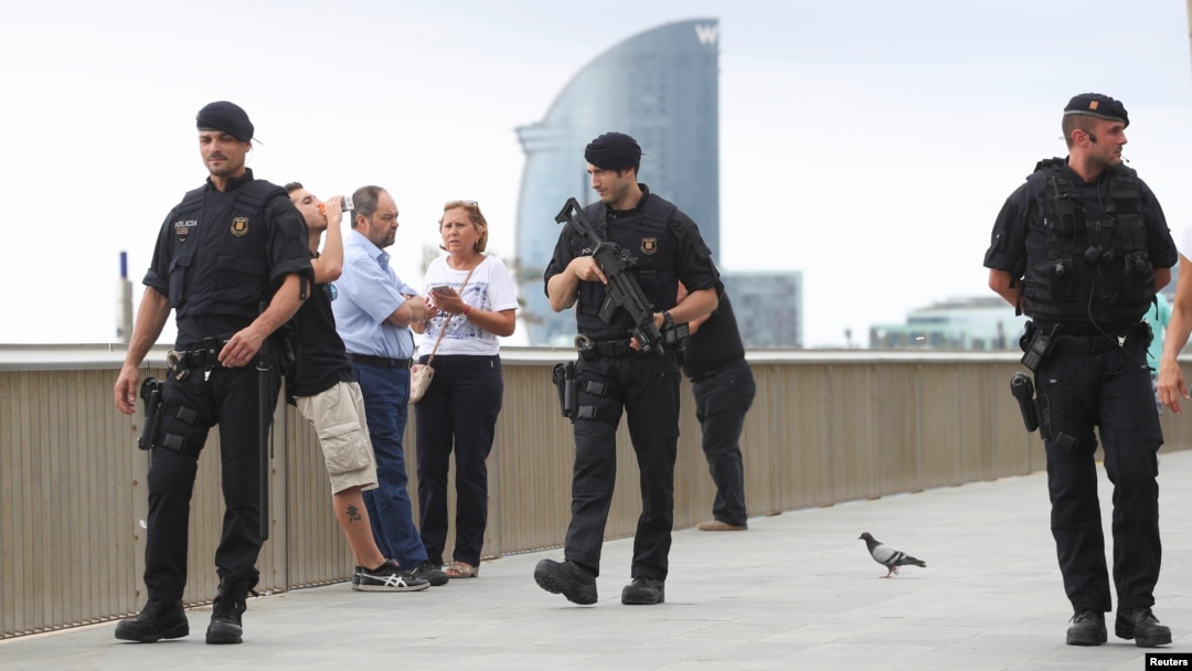 Armed Catalan Mossos d'Esquadra officers patrol along La Barceloneta beach in Barcelona, Spain, Aug. 19, 2017