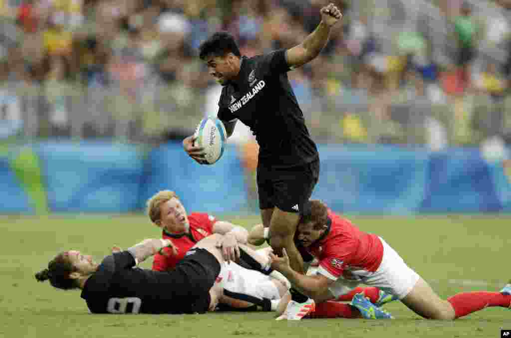 Regan Ware dari Selandia Baru (atas) dihadang para pemain Inggris dalam pertandingan rugby (10/8). (AP/Themba Hadebe)