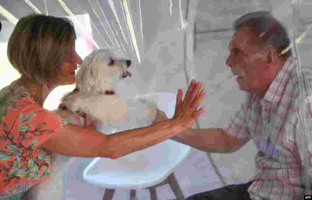 A woman visits her husband at a retirement home in Bourbourg, North of France, where a double entry bubble has been installed to allow visits without risk of contamination, as part of a measure against the spread of the Covid-19.