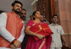 Indian Finance Minister Nirmala Sitharaman, center, and junior Finance Minister Anurag Thakur, left, stands for the media at the parliament house before presenting the annual federal budget in New Delhi, India, Friday, July 5, 2019.