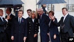 Belgian Prime Minister Charles Michel, center, and his partner Amelie Derbaudrenghien, second right, are greeted by French President Emmanuel Macron, left, and his wife Brigitte Macron as they arrive at the Elysee Palace in Paris to participate in a World