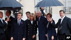 Belgian Prime Minister Charles Michel, center, and his partner Amelie Derbaudrenghien, second right, are greeted by French President Emmanuel Macron, left, and his wife Brigitte Macron as they arrive at the Elysee Palace in Paris to participate in a World