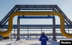 DOSSIER – Un employé portant une veste de marque passe devant une partie du gazoduc Power Of Siberia de Gazprom à la station de compression Atamanskaya à l'extérieur de la ville extrême-orientale de Svobodny, dans la région de l'Amour, en Russie, le 29 novembre 2019.