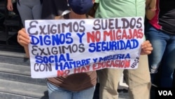 Una manifestante venezolana sostiene una pancarta en una protesta por mejores salarios, en Caracas. [Foto: VOA/Álvaro Algara].