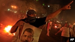 A Supporter of ousted President Mohammed Morsi holds a poster of him during clashes in downtown Cairo, Egypt. July 15, 2013. 