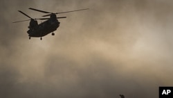 A US Marine tries to shelter from the dust as a Chinook helicopter arrives to pick up supplies at Forward Operating Base Edi in the Helmand Province of southern Afghanistan,June 9, 2011 file photo