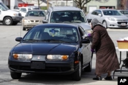 Bertha Brown hands a plastic bag filled with bread and a cup to a church member during a drive-thru Holy Communion on Good Friday at Grace Apostolic Church, in Indianapolis, April 10, 2020.