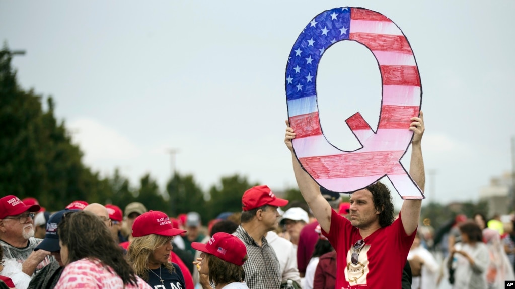 FILE - In this Aug. 2, 2018, file photo, a protesters holds a Q sign waits in line with others to enter a campaign rally with President Donald Trump in Wilkes-Barre, Pa. 