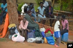 In this Tuesday July 12, 2016 photo, people take shelter near the All Saints Church in Juba, South Sudan. Embassies and aid organizations in South Sudan were trying to evacuate staff from the capital, Juba, on Tuesday as a precarious calm settled over the city following several days of deadly clashes.