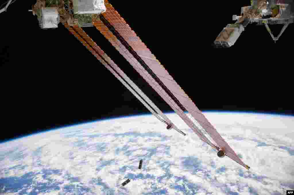 In the grasp of the Japanese robotic arm, the CubeSat deployer (upper right) releases a pair of NanoRacks CubeSat miniature satellites (bottom center) in this NASA image.