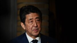 Japan's Prime Minister Shinzo Abe talks to journalists in front of the prime minister's residence in Tokyo, Tuesday, March 24, 2020.
