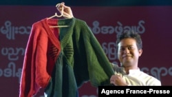 FILE - Myanmar actor Pyay Ti Oo displays a jumper knitted by then-opposition leader Aung San Suu Kyi, at an auction in Yangon, Myanmar, Dec. 27, 2012. He and two other Myanmar celebrities reportedly have been jailed for speaking out against the February coup.