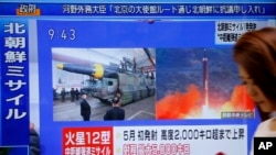 Seorang perempuan berjalan melewati layar TV yang menyiarkan berita peluncuran misil Korea Utara di Tokyo, 29 Agustus 2017.