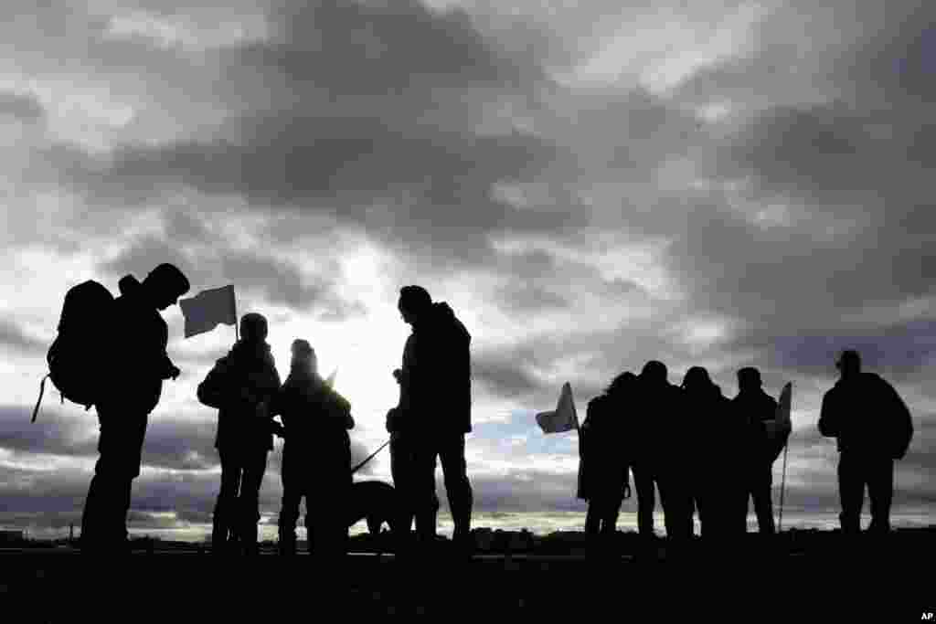 Para demonstran memegang bendera putih nampak seperti siluet di depan langit yang mendung saat diluncurkannya &quot;Pawai Sipil untuk Aleppo (Civil March for Aleppo)&quot; di lapangan bekas bandara Tempelhof di Berlin, Jerman.