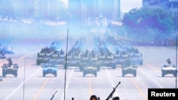 Soldiers of the People's Liberation Army (PLA) of China roll on their armoured vehicles to Tiananmen Square as others are shown on a big screen during the military parade marking the 70th anniversary of the end of World War II, in Beijing, China, Sept. 3,