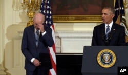 FILE - President Barack Obama, right, honors Vice President Joe Biden, left, during a ceremony in the State Dining Room of the White House in Washington, Jan. 12, 2017.