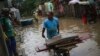 Para warga membereskan barang-barang di rumah mereka yang terendam banjir di Itapetinga, Bahia, Brazil, pada 28 Desember 2021. (Foto: AP/Raphael Muller)