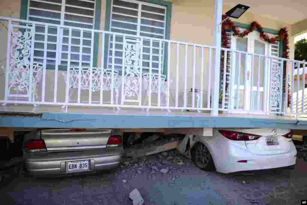 Cars are crushed under a home that collapsed after an 5.8-magnitude earthquake hit Guanica, Puerto Rico.
