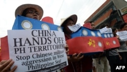 FILE - Filipino students hold replicas of Chinese maritime surveillance ships as they shout anti-Chinese slogans during a rally in Manila March 3, 2016, to denounce reported Chinese vessels dropping anchor near a South China Sea atoll.