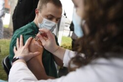 Colleen Teevan, Manajer Klinik Farmasi Sistem di Hartford HealthCare, menyuntikkan vaksin COVID-19 produksi Pfizer-BioNTech kepada petugas kesehatan Connor Paleski di luar Rumah Sakit Hartford di Hartford, Connecticut, 14 Desember 2020,. (Foto: AP / Jessica Hil