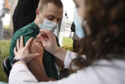 Colleen Teevan, System Pharmacy Clinical Manager at Hartford HealthCare, administers the Pfizer-BioNTech vaccine for COVID-19 to healthcare worker Connor Paleski outside of Hartford Hospital, Monday, Dec. 14, 2020, in Hartford, Conn. (AP Photo/Jessica Hil