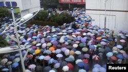 Local residents gather in front of a municipal government building in Shifang county, Sichuan province, in this handout picture taken July 2, 2012. 