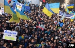 Students hold placards and flags as thousands rally in the western Ukrainian city of Lviv during a rally of pro-European supporters, Nov. 27, 2013.
