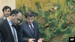 Turkish Foreign Minister Ahmet Davutoglu (R) speaks to Vice-Chairman of the Executive Board of the Libyan National Transitional Congress Ali al-Issawi (L) before a news conference after their meeting in the rebel-held Benghazi, Libya, July 3, 2011