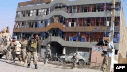 US soldiers and Afghan security forces stand guard at the site of a car bomb in front of a branch of the Kabul bank in Kandahar on 27 Dec 2010