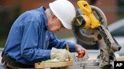 Former president Jimmy Carter measures before making a cut with a miter saw at a Habitat for Humanity building site, Nov. 2, 2015, in Memphis, Tennessee.