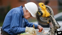 Former president Jimmy Carter measures before making a cut with a miter saw at a Habitat for Humanity building site, Nov. 2, 2015, in Memphis, Tennessee.