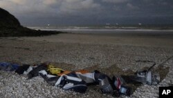 FILE- Life jackets, sleeping bags and damaged inflatable small boat lie on the shore in Wimereux, northern France, Nov. 26, 2021 in Calais, northern France.